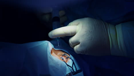 corrección de la visión con láser. un paciente y un equipo de cirujanos en la sala de operaciones durante una cirugía oftalmológica. especulo del párpado. tratamiento de lasik. paciente bajo una cubierta estéril