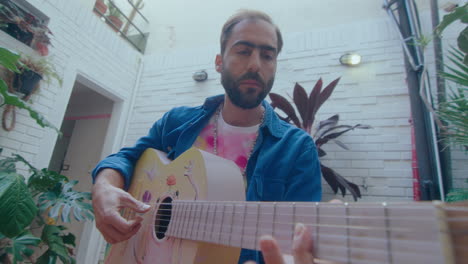 man playing the guitar outdoors on home patio garden