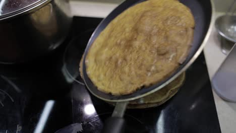 The-process-of-cooking-homemade-pancakes.-Woman-puts-pancake-from-pan-to-plate