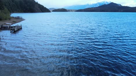 flying over the waves of lake nahuel huapi and revealing its beautiful mountains and forest in bariloche, patagonia