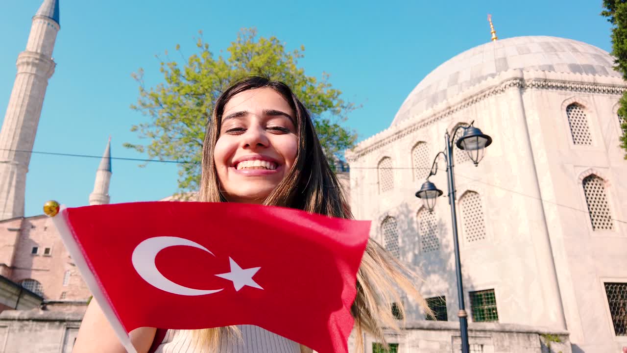 Cámara lenta: Hermosas jóvenes ondeando la bandera turca frente a un edificio antiguo en Estambul, Turquía. Concepto de viaje.