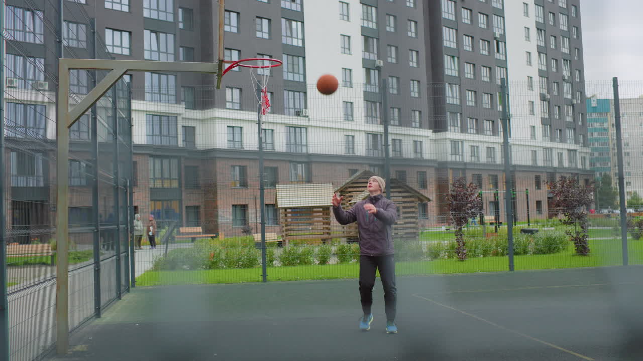 man juggling basketball on city court, playful skill shots and bounce drills near residential blocks, casual jacket and sneakers, bright energy and quick footwork, solo practice with community