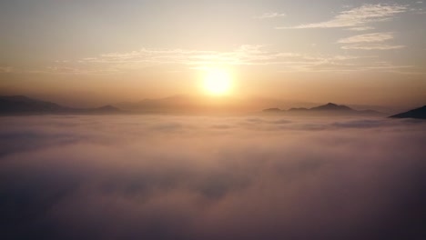 amazing rising drone shot in between clouds of a sunrise in the hills of the desert of lima