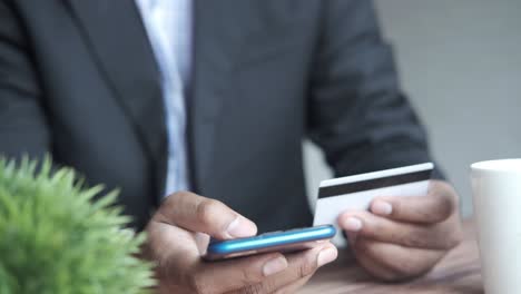 hombre de negocios haciendo pagos en línea usando teléfono inteligente y tarjeta de crédito