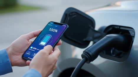 person monitoring electric car charging status with a smartphone app