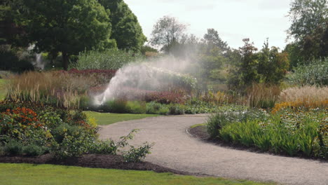 sprinkler system watering gardens of flowers part 2 - handheld slow motion