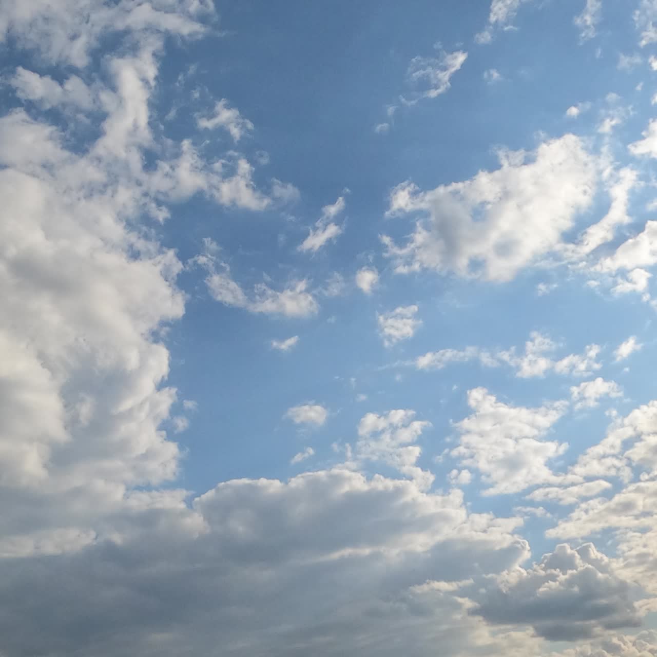 Sunny blue skies with light white clouds flying by the horizon. Big grey cloud approaches and covers the sky. Timelapse