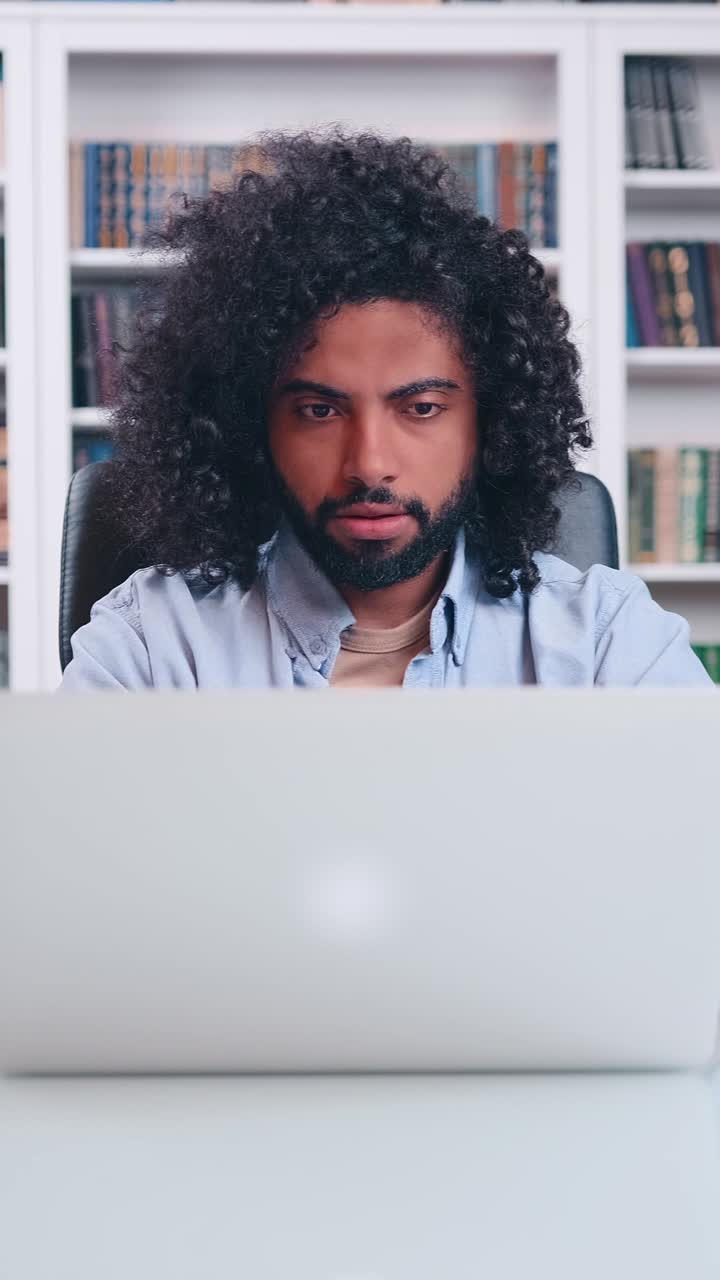 Focused man working on a laptop in a serene library setting