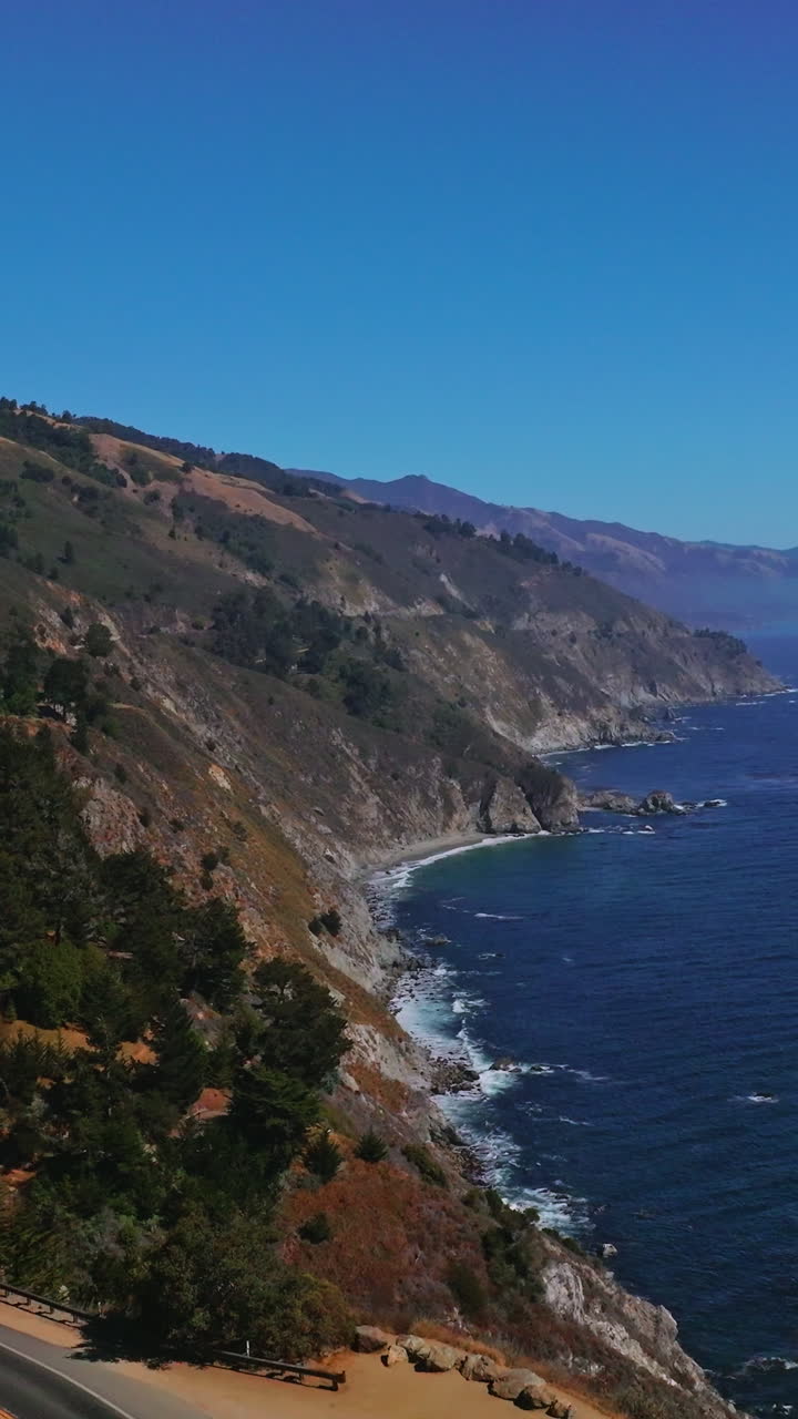 Splendid scenery of mountains meeting the ocean. Roads in the rocks among the pine trees. Big Sur Morro Bay in California, USA. Vertical video