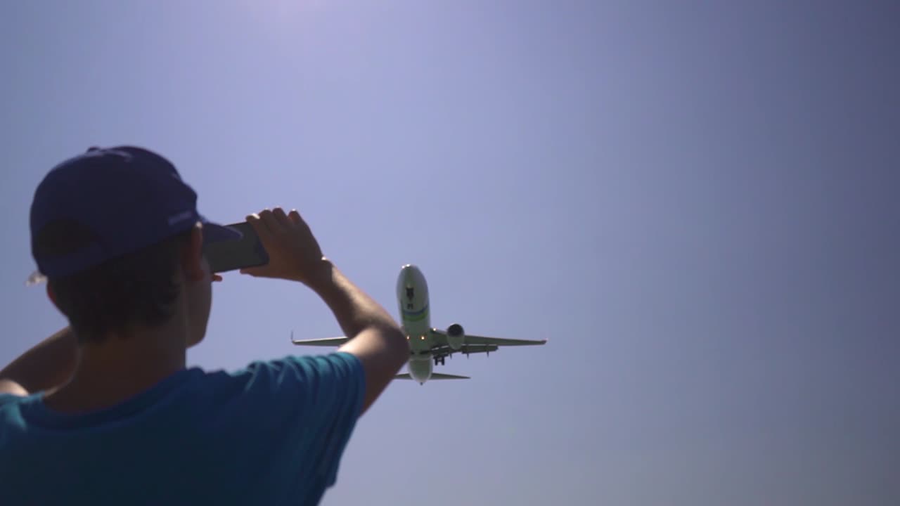 사람들은 비행기가 착륙을 위해 가까이 날아갈 때 손을 흔들며 환호하고 있습니다.