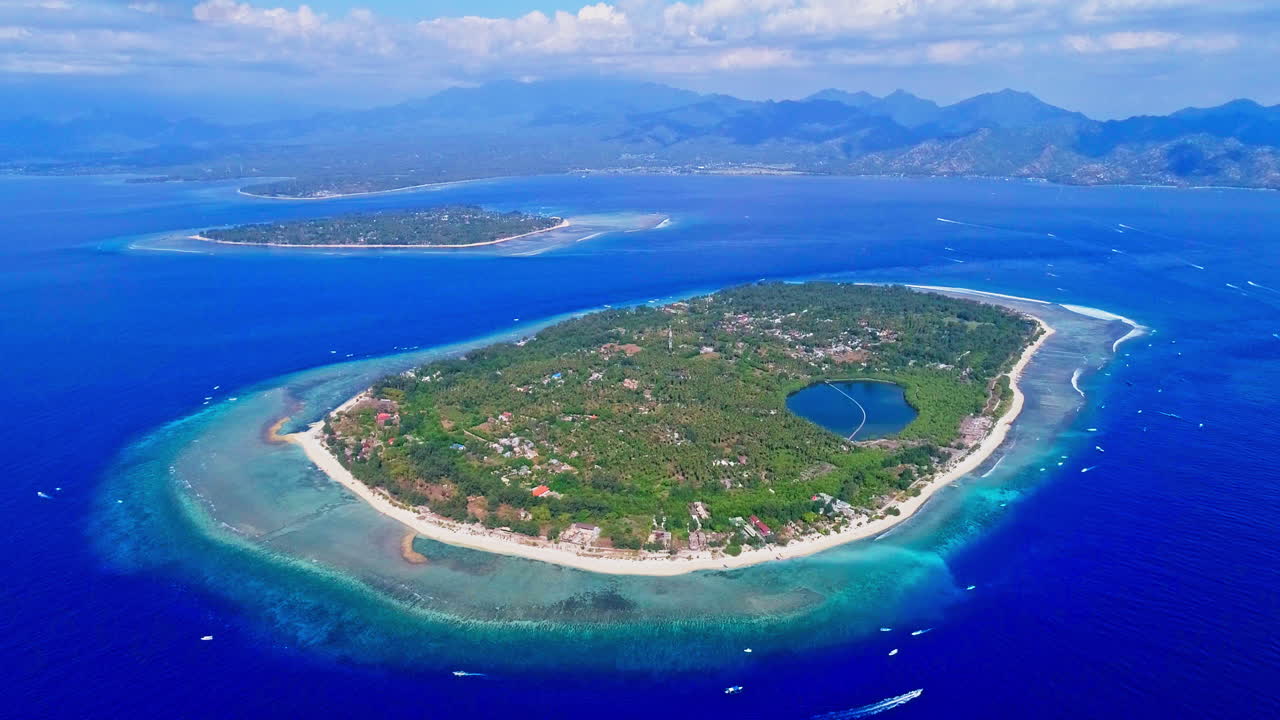 Stunning aerial footage of the Gili Islands, Indonesia. Crystal-clear waters, white sand beaches, coral reefs, and boats in paradise. Ideal for travel, nature, and tropical themes