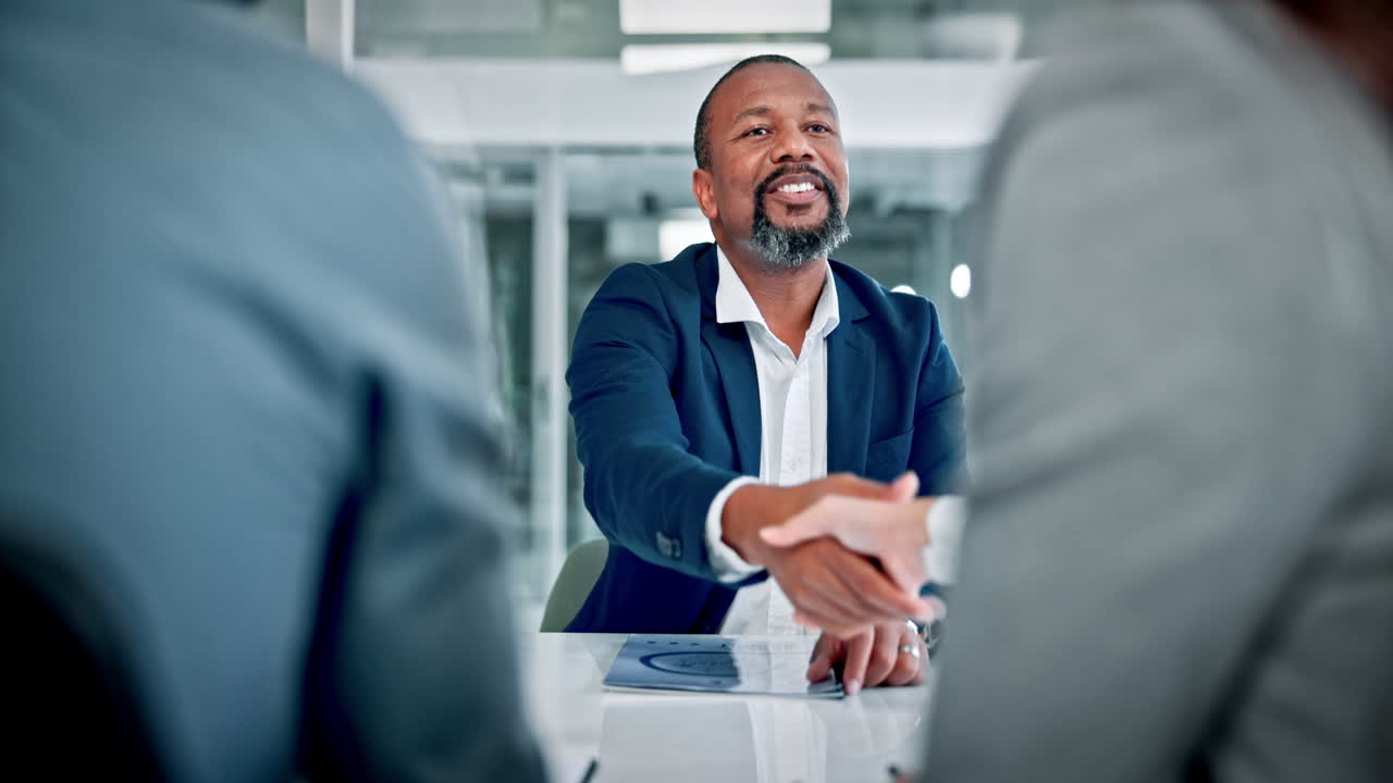 Smiling Businessman Shaking Hands in a Modern Office Meeting
