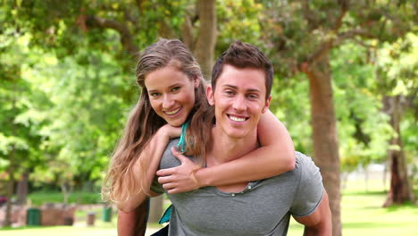 Woman-jumps-onto-her-friends-back-for-a-piggyback-before-they-look-at-the-camera-while-smiling