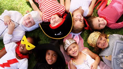 group of kids in various costumes lying on grass