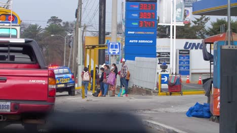 people waiting at a bus stop near a gas station in guatemala