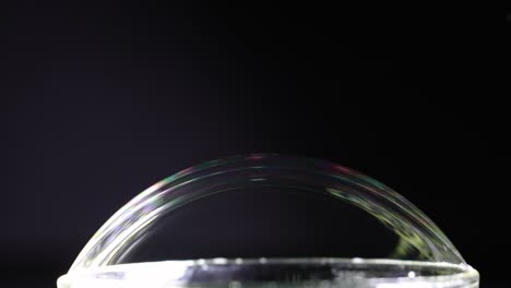 a soap bubble displays vibrant color reflections against a dark background, captured in a sequence of frames