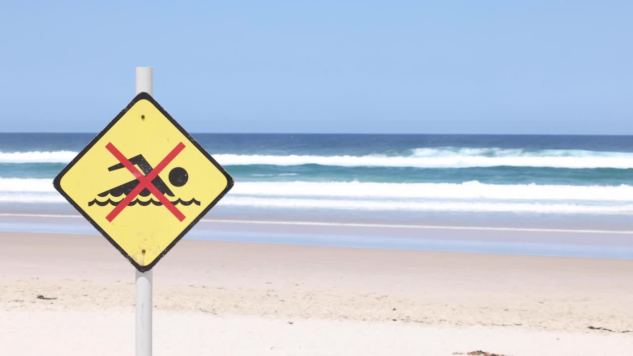 파도 의 배경 에 비해 해변 에 있는 경고 표지판
