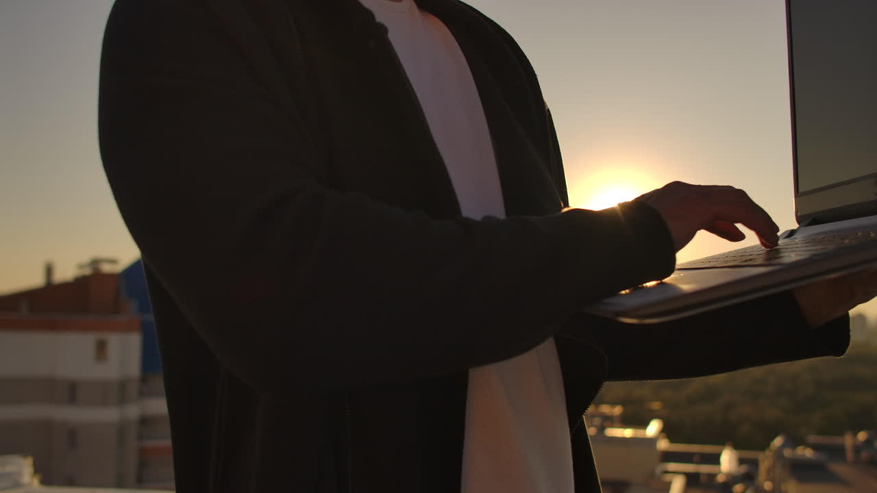 city view와 forex 차트와 함께 옥상에서 노트북을 사용합니다. 해킹과 통계 개념. 서서히 움직이는 해커가 노트북에 소프트웨어 코드를 작성하는 일.