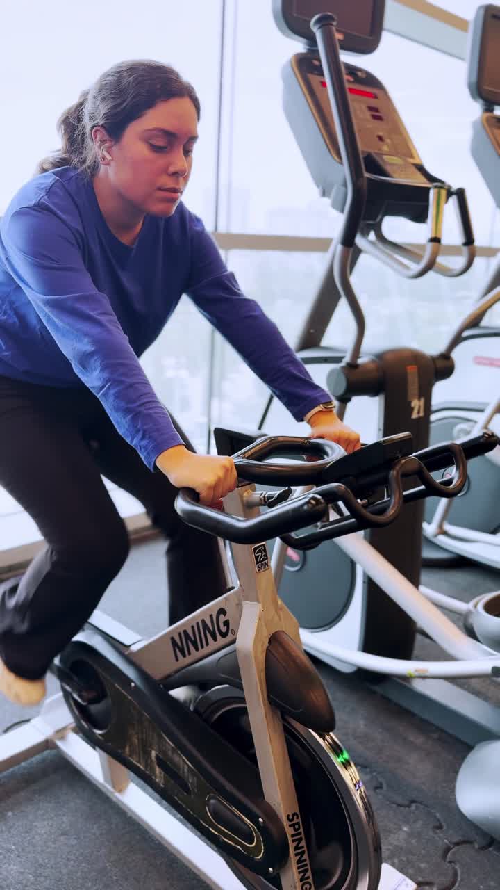 A woman is riding a stationary bike in a gym