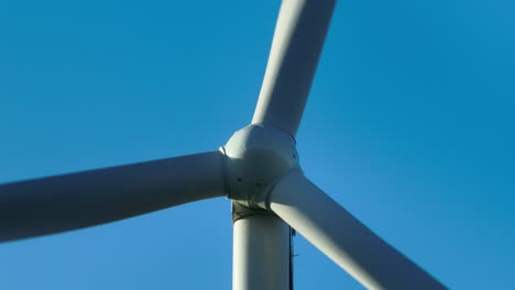 Close-up-of-a-spinning-wind-turbine-against-a-clear-blue-sky