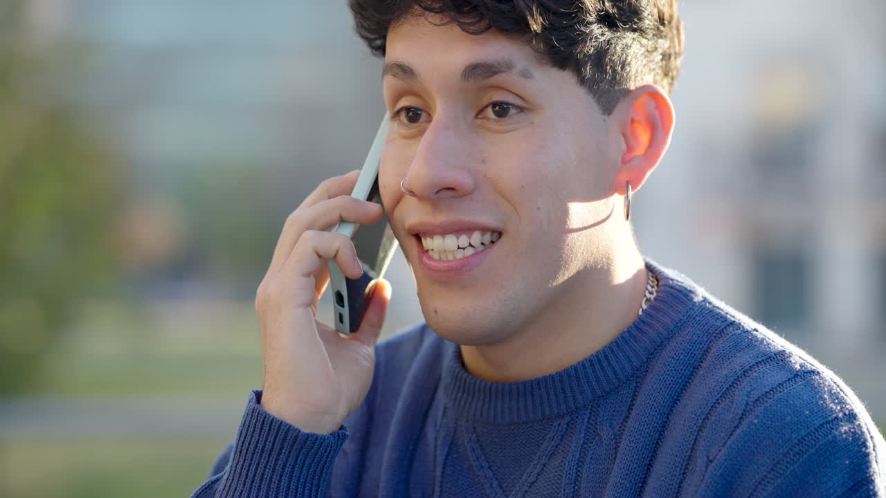 Young latino man talking on mobile phone outdoors