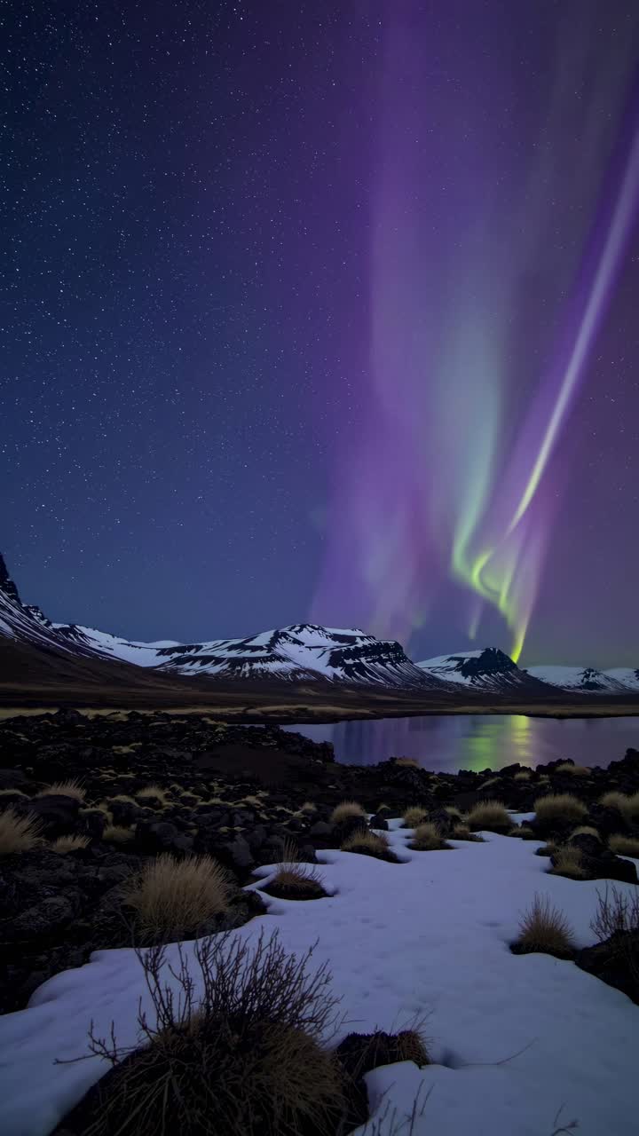 Stunning wide-angle video shot of vibrant aurora borealis over snowy landscape, capturing dynamic