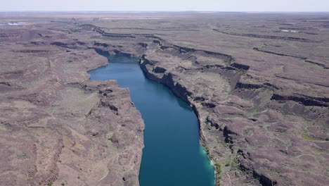 Die-Aufsteigende-Luftaufnahme-Eines-Tiefen-Sees-Zeigt-Eine-Raue,-Trockene-Landschaft-In-Wa-Scablands