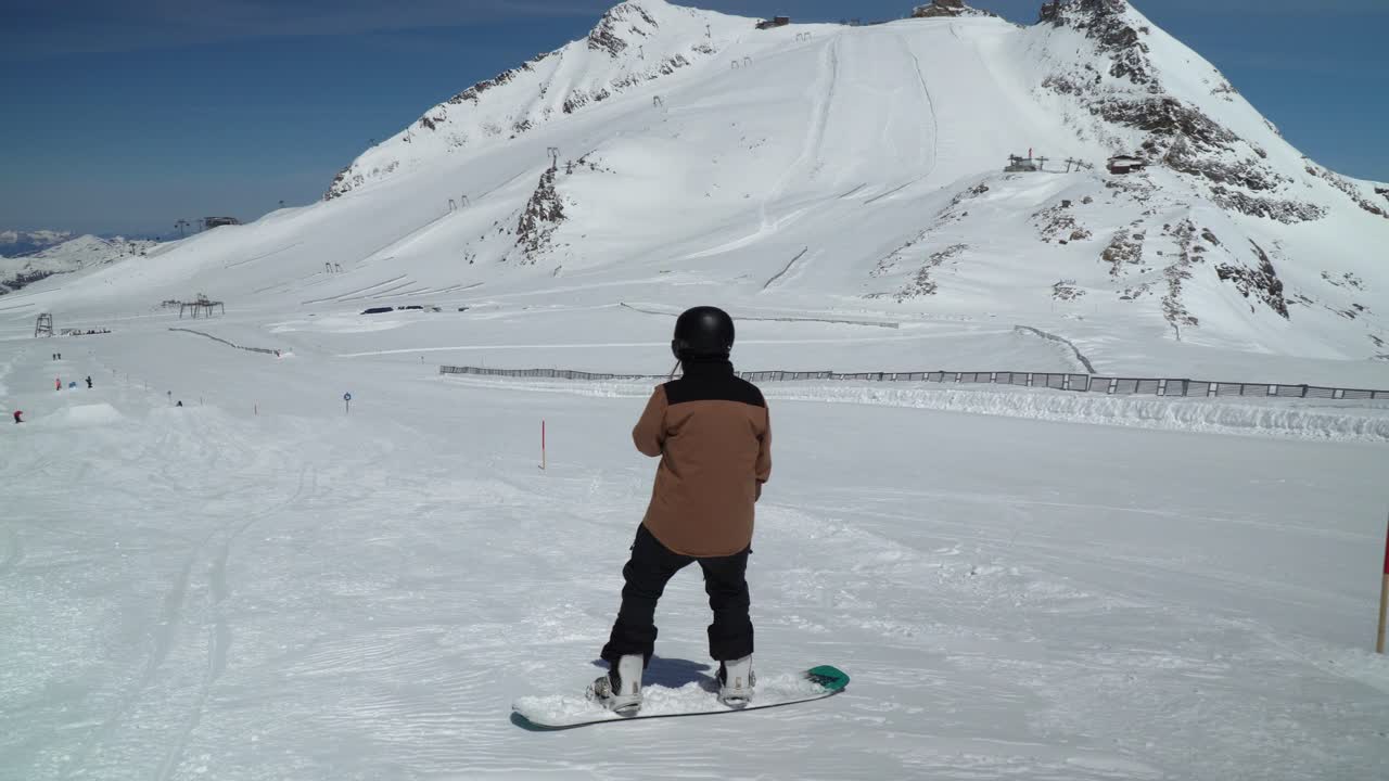 Snowboarding girl sideslipping or sliding on edge in ski resort high on glacier in Austria. Slopes of Hintertux, ski resort that is open 365 days a year.