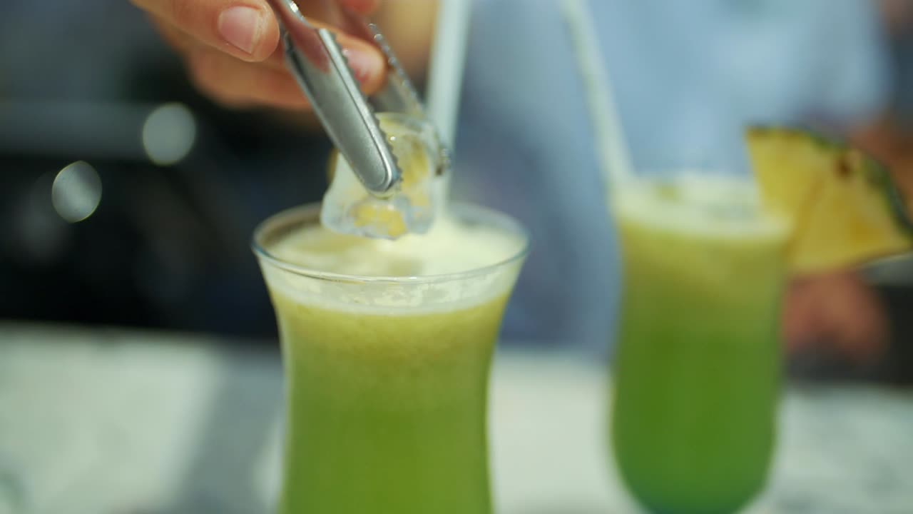 el hombre arroja hielo al jugo fresco en un vaso