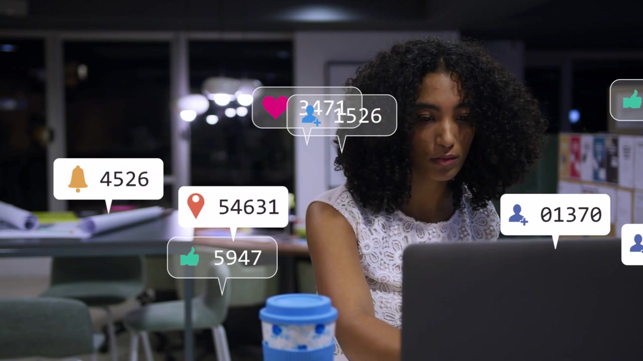 Woman typing on laptop and jotting notes sparking social media notifications while tracking metrics