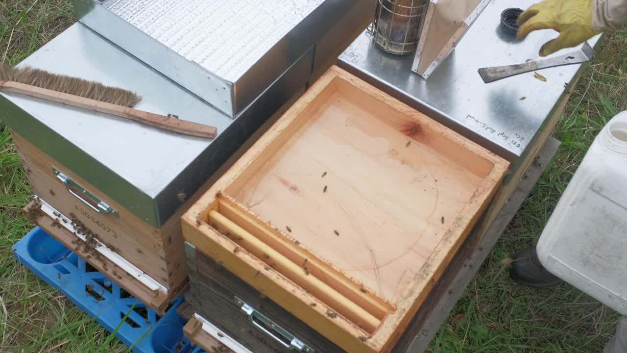 Footage of a beekeeper putting a wax foundation or honeycomb base into the frame-he is pouring liquid wax into the edges to make the base firm