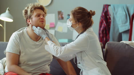 Médico-Con-Mascarilla-Tomando-Un-Hisopo-De-Garganta-Durante-La-Consulta-En-El-Hogar