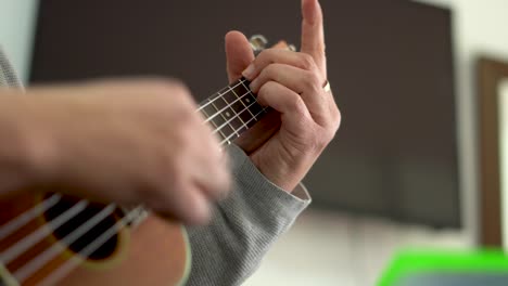 male hands playing the ukelele at home