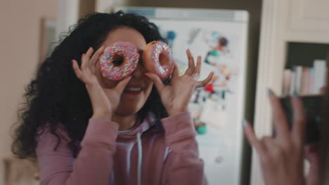 funny teenage girls posing with donuts taking photos using smartphone sharing on social media enjoying hanging out on weekend in kitchen