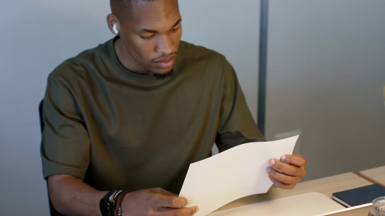 Man writing notes, reviewing charts, sparking marketing alerts floating over laptop, then subsiding