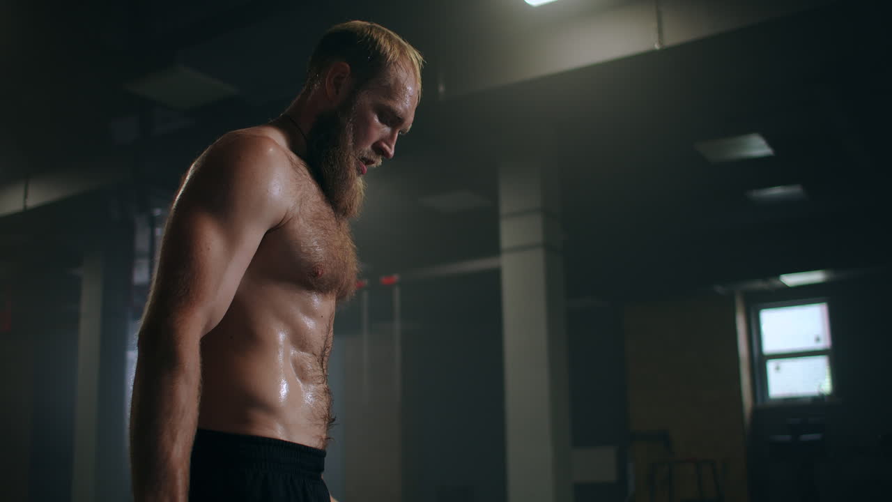 체육관 에 있는 피곤 한 남성 운동 선수 는 휴식 을 취하고 운동 을 하기 위해 준비 하고 있다. 느리게 움직이는  ⁇  흘리는 운동 선수 는 심한 호흡 을 하고 운동 에 집중 한다