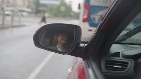 Reflejo-De-Una-Mujer-Feliz-Sonriendo-En-El-Espejo-Lateral-Del-Auto-Rojo