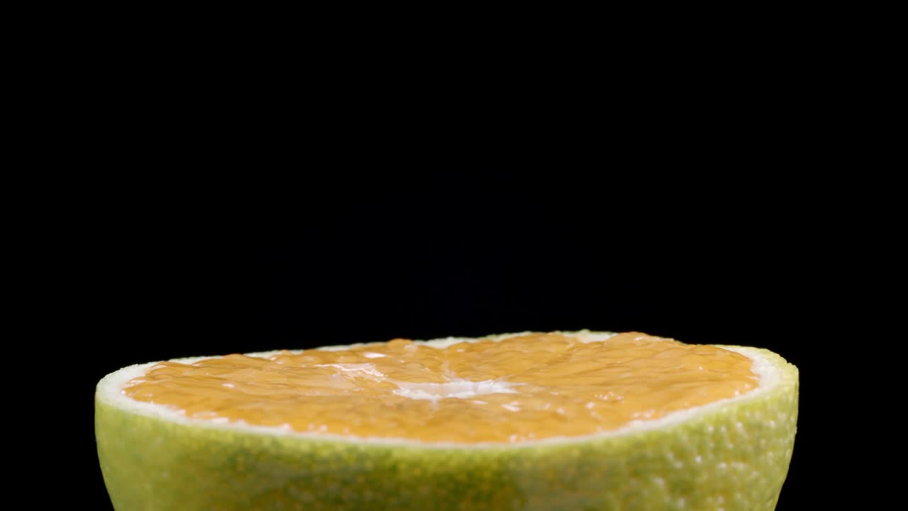 Video of rotating tangerine half on black background
