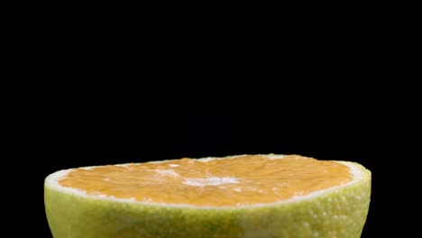 video de la mitad giratoria de la mandarina sobre un fondo negro