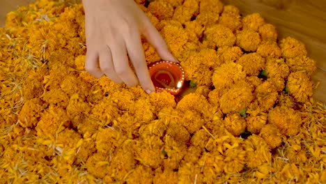 indian woman placing earthen lamp in rangoli