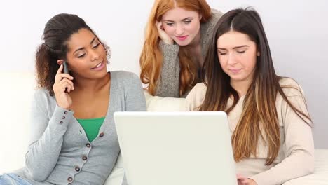 Cute-women-relaxing-on-couch-while-using-notebook-and-smartphone