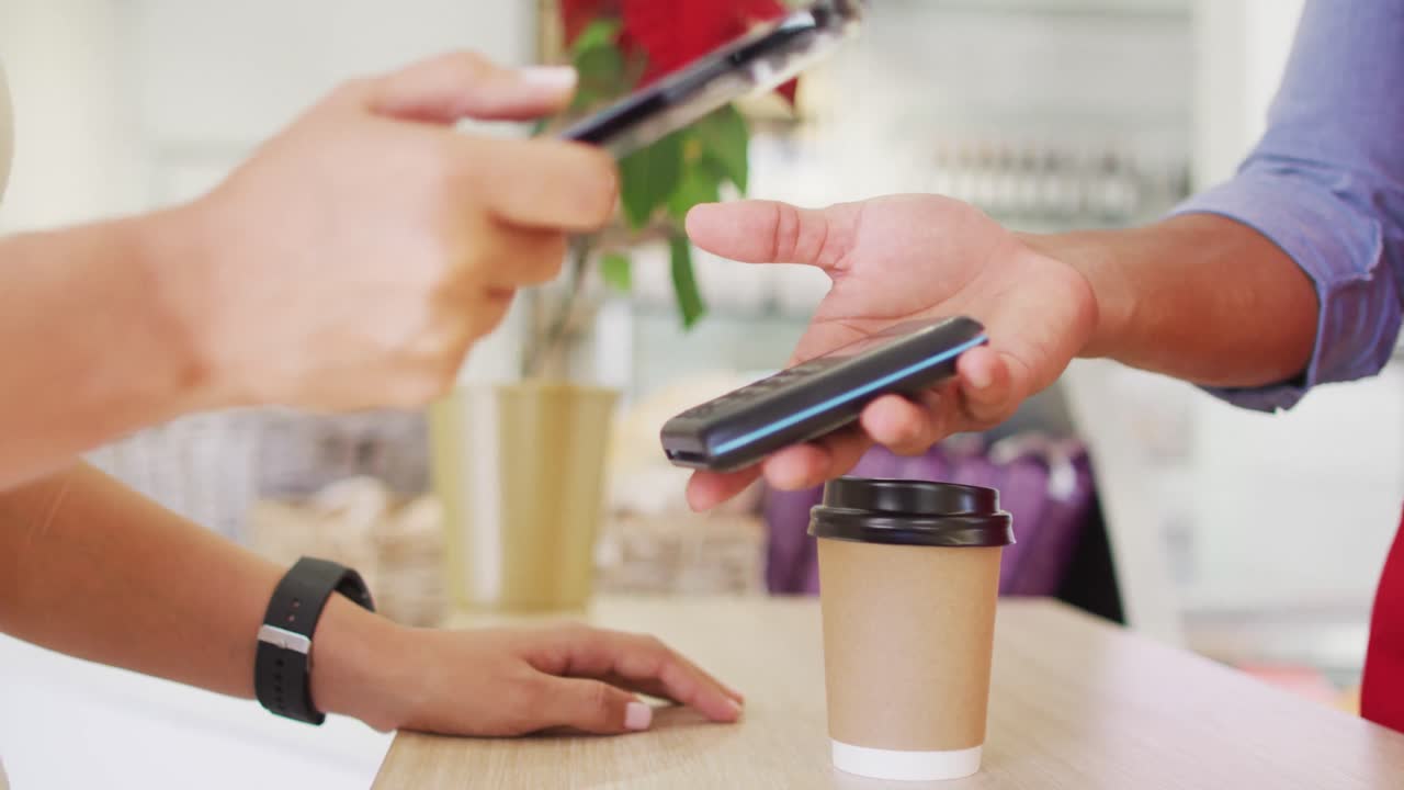 video de las manos de una mujer biracial pagando con un reloj inteligente por café