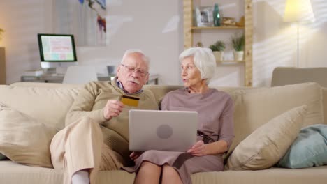 Retired-Couple-Sitting-On-Sofa-At-Home-And-Shopping-Online-Together-1