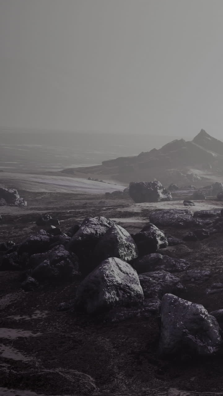 Mysterious landscape with stones and distant mountains in gray fog