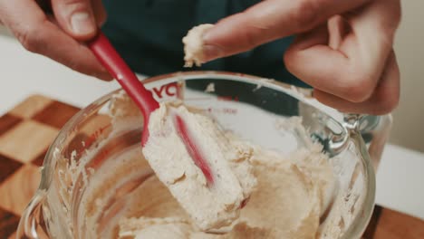 Chef-checks-consistency-of-mixed-ingredients-for-homemade-butter-inside-glass-cooking-bowl