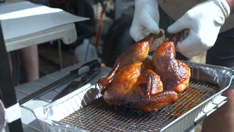 bbq chicken being taken off of a rack and placed on a table for slicing