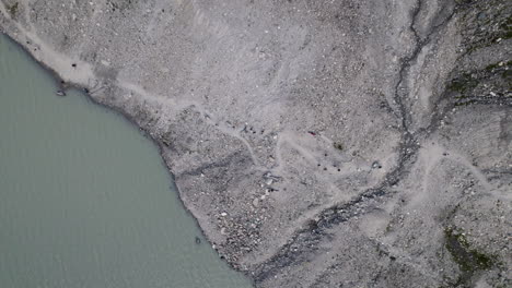 Top-down-aerial-view-of-hiking-trail-alongside-Pasterze-Glacier-Lake-at-High-Tauern-National-Park,-Austria