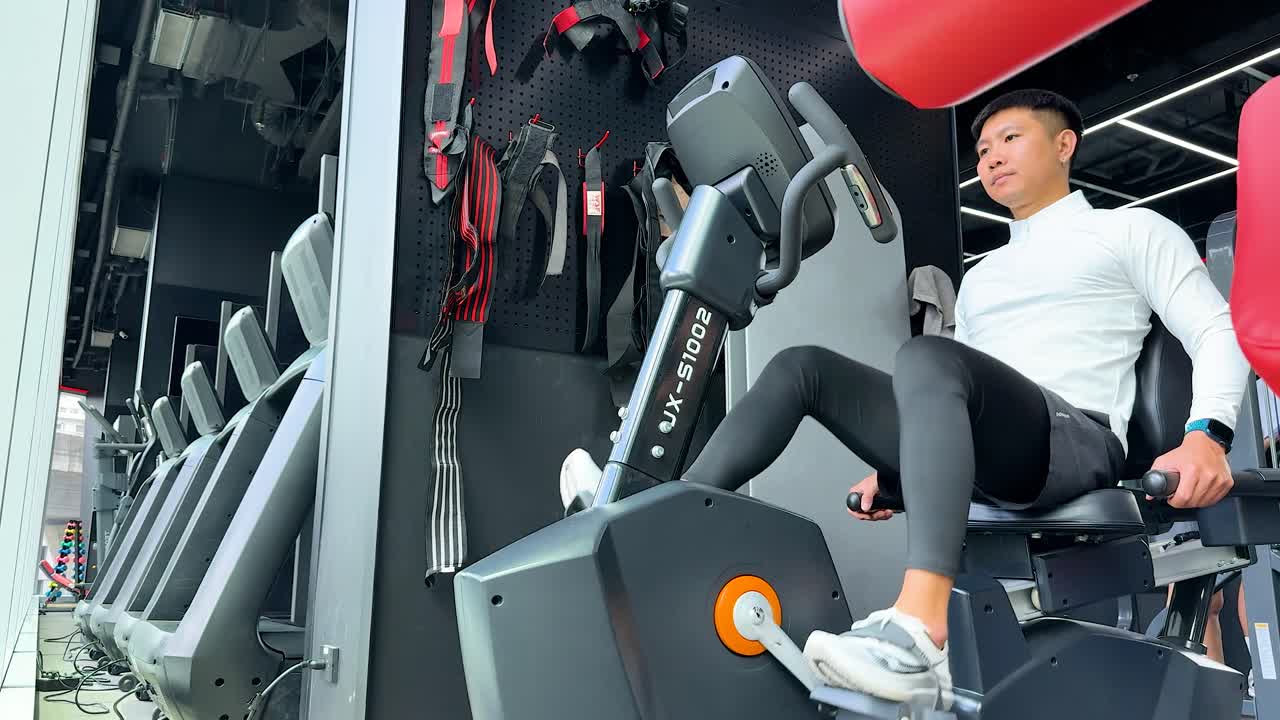 Uomo determinato che si allena su una cyclette orizzontale magnetica all'interno di un moderno centro fitness
