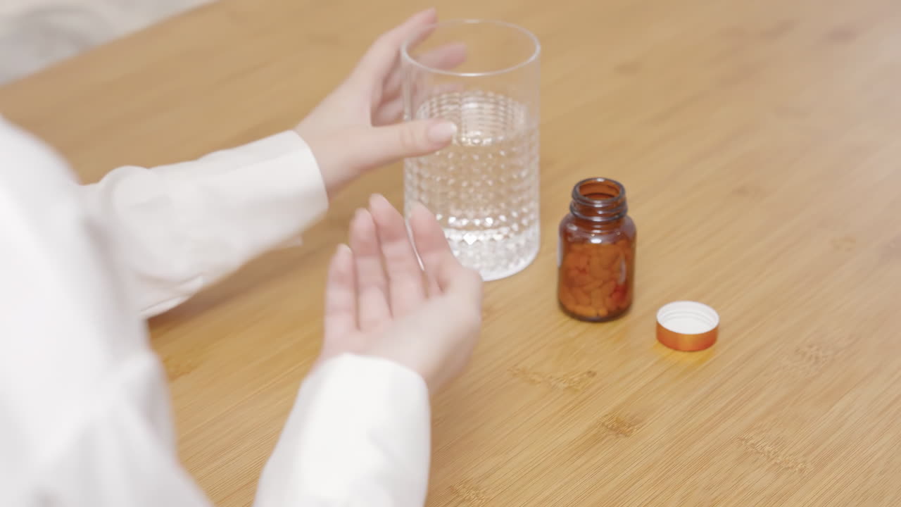 Giovane donna che assume puntualmente i suoi farmaci a casa, come pillole orali per donne, farmaci per la preconcezione (acido folico) da una bottiglia bianca o capsule per la perdita di peso e la dieta, per la cura della salute e il sollievo da disturbi.