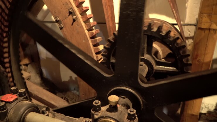 Spinning Cogwheels Gear Wheels in wooden historical old Mill - Closeup handheld panning right